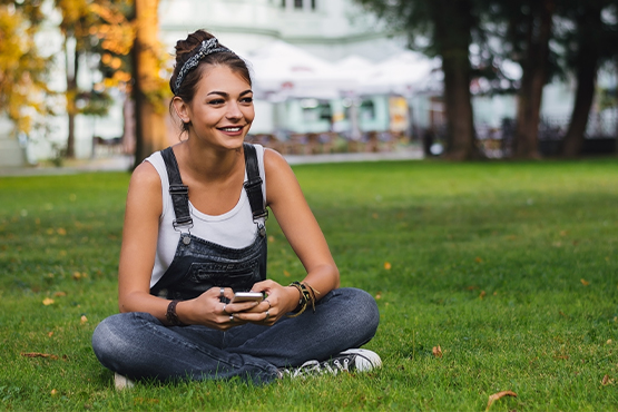 girl sits in grass after protecting her device and securing her data at gate city bank