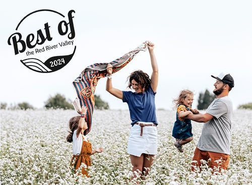 Best of the Red River Valley logo and a young family of four playing together in a field of wildflowers outside of Fargo, ND