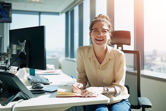 a happy employee in her bright, scenic office jots notes after reading Gate City Investment Services’ SECURE 2.0 takeaways