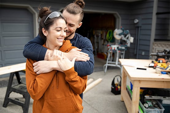 a happy couple pauses from a home project to hug after reading Gate City Bank’s article on a home equity loan vs. HELOC