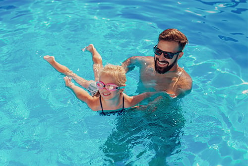 a happy dad and daughter swim together in the family pool they had put in, thanks to a HELOC from Gate City Bank