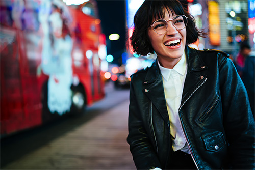 Laughing young woman in a leather jacket, enjoying the vibrant nightlife in downtown Fargo, ND