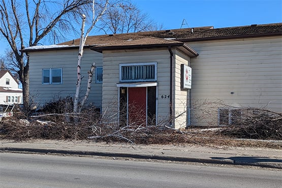 A formally abandoned building at 624 North Washington St. in Grand Forks, ND, with brush and other debris lying out front