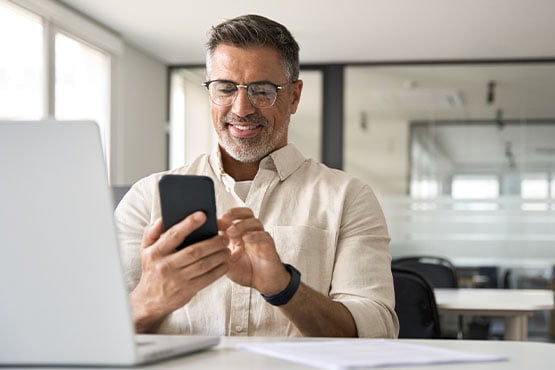50-something small business manager smiles while reading free Gate City Bank business articles on his phone
