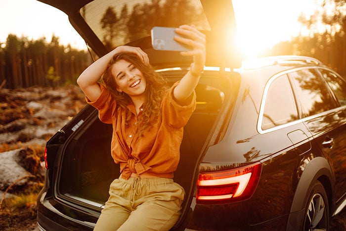 young woman taking a selfie at sunset in the back of her new crossover, purchased with a Gate City Bank auto loan in Fargo, ND