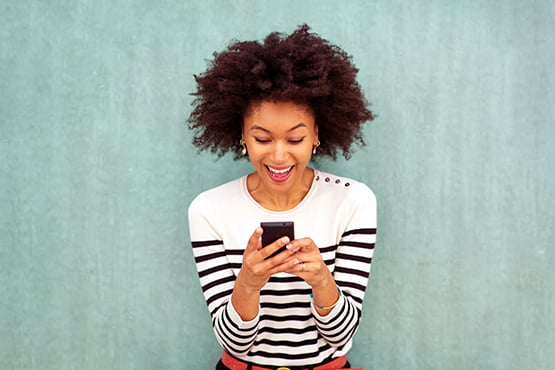 cheerful young woman checks her phone, knowing she is covered with overdraft protection options from Gate City Bank