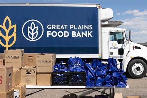 Side view of a Great Plains Food Bank truck, boxes of food drive donations and Gate City Bank blue bags