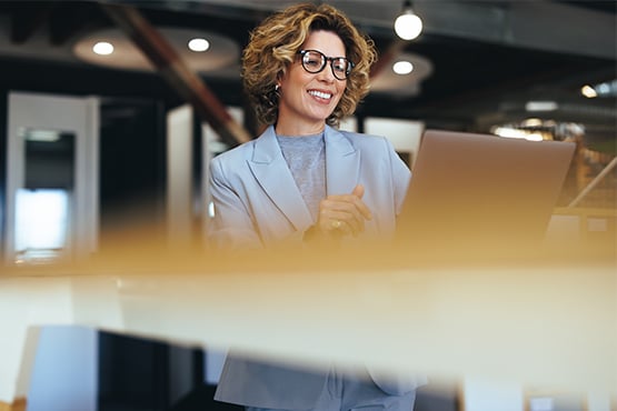 curly-haired businesswoman in a blazer, selecting her best business savings account online at her office in Grand Forks, ND