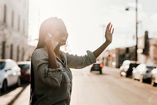 Confident young woman waving to a friend on the streets of downtown Moorhead, MN