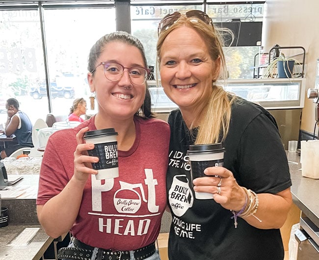 Bully Brew owner Sandy Luck with one of her staff members, holding coffee and smiling for a snapshot in Grand Forks, ND