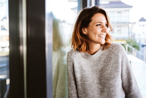 Relaxed young woman in a beige sweater outdoors in North Dakota, getting ready to go to her favorite West Fargo bank