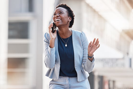 Laughing businesswoman in a gray suit, talking on the phone with her Gate City Bank business banker in downtown Fargo, ND