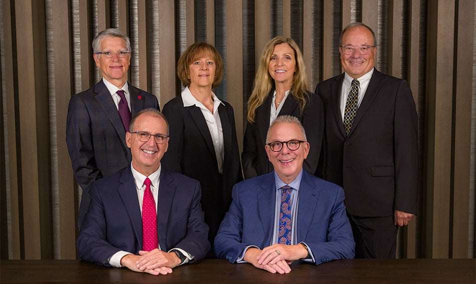 Gate City Bank's board members gather next to a conference room table and smile at the camera