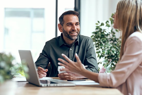 a mortgage lender in a green button-down sits down to answer his customer’s questions about her Gate City Bank home loan