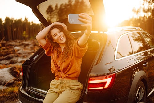 young woman taking a selfie at sunset in the back of her new crossover, purchased with a Gate City Bank auto loan in Fargo, ND