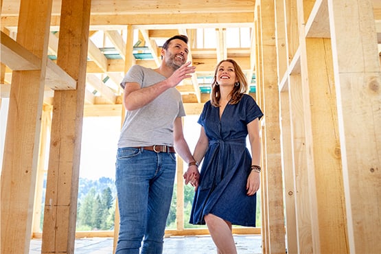 a couple holds hands inside the frame of a future home after learning steps for building your dream home from Gate City Bank