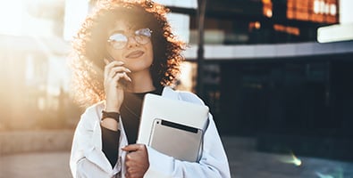 Curly-haired woman businesswoman with glasses, talking on the phone with her Gate City financial advisor in Fargo, ND