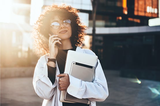 Curly-haired woman businesswoman with glasses, talking on the phone with her Gate City financial advisor in Fargo, ND