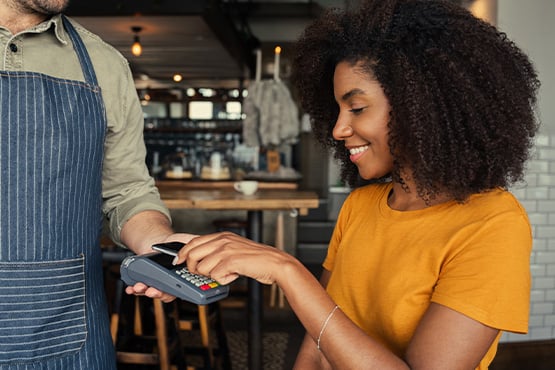 A young woman buys a coffee with a digital payment app.